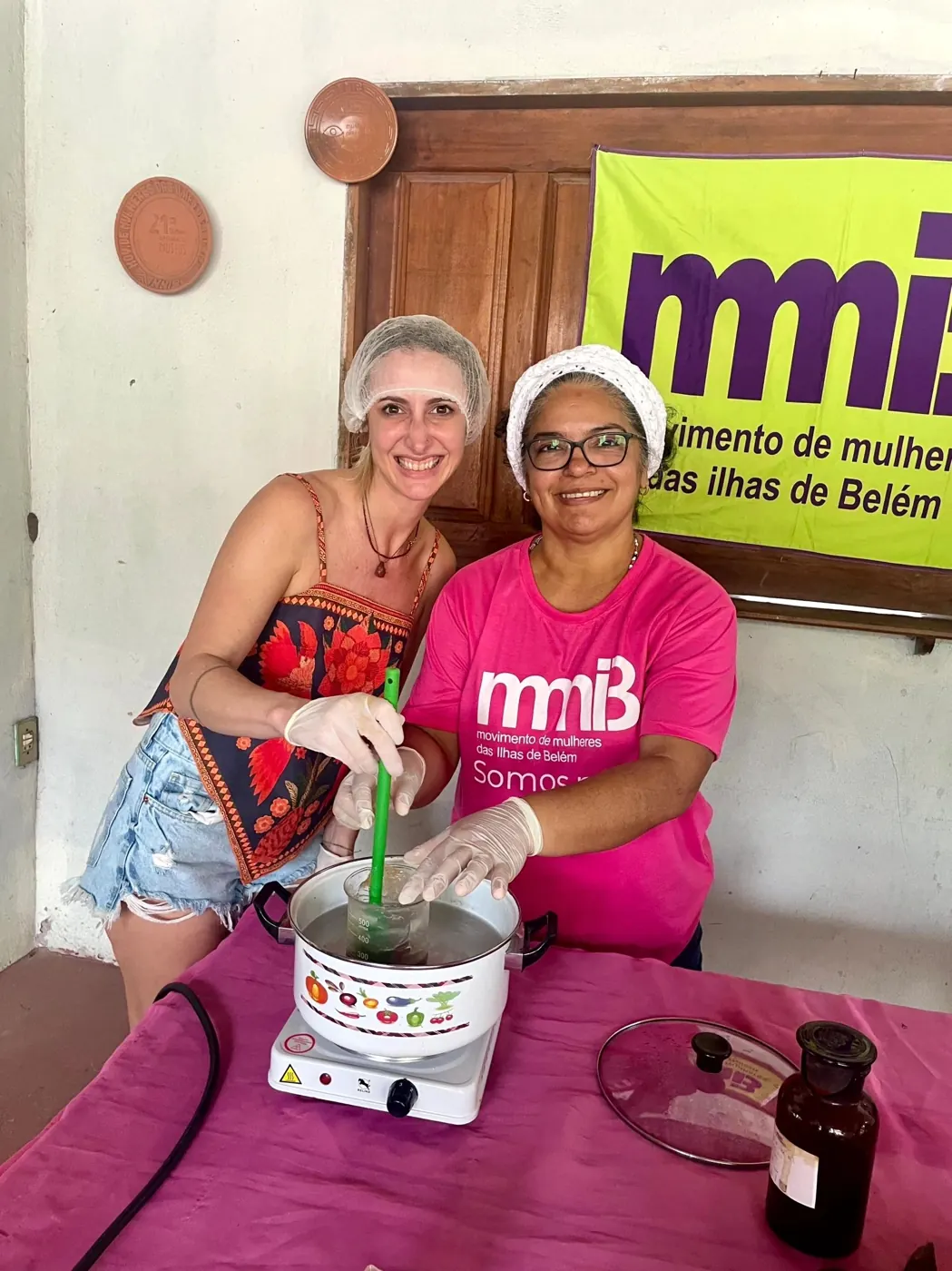 Priscila und eine Frau des MMIB rühren gemeinsam in einem Topf mit Pflanzenextrakt