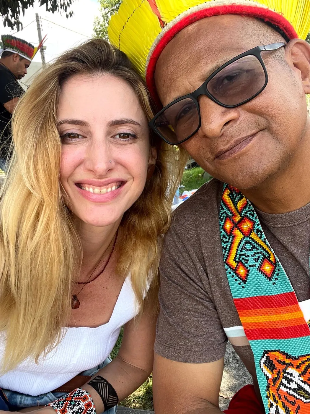 Selfie von Priscila mit einem indigenen Mann mit Federkopfschmuck und Körperbemalung